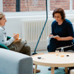 Two women sit in chairs and talk